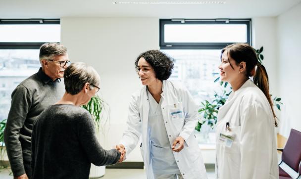 Clinical Doctors Greeting Elderly Couple