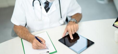 Arzt macht Notizen und liest auf dem Tablet