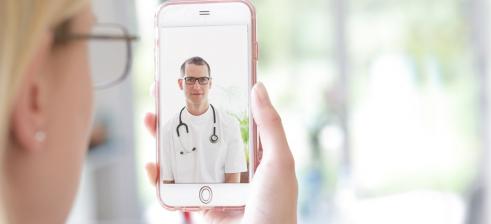 Patientin spricht über ihr iphone zum Arzt in einer Videosprechstunde